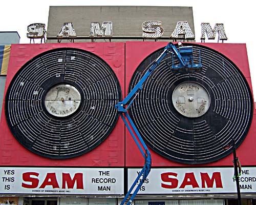 construction worker on manlift works on Sam the record man sign on Young Street, Toronto