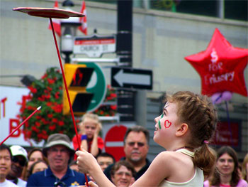2006 Toronto Buskerfest - child from the crowd helps with a performance - spinning plate on  a pole