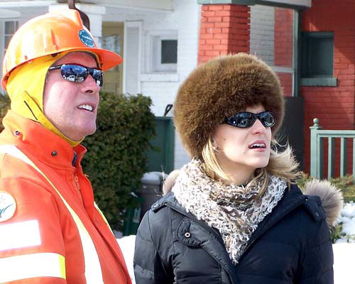 MairiAnna Bachynsky  of CTV news talks with a member of Toronto Hydro about a large tree branch that fell down on a house and overhead hydro wires.