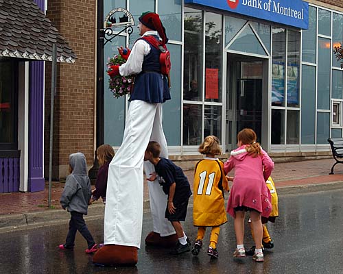 A Taste of Acton stilt walker with children going in between stilts